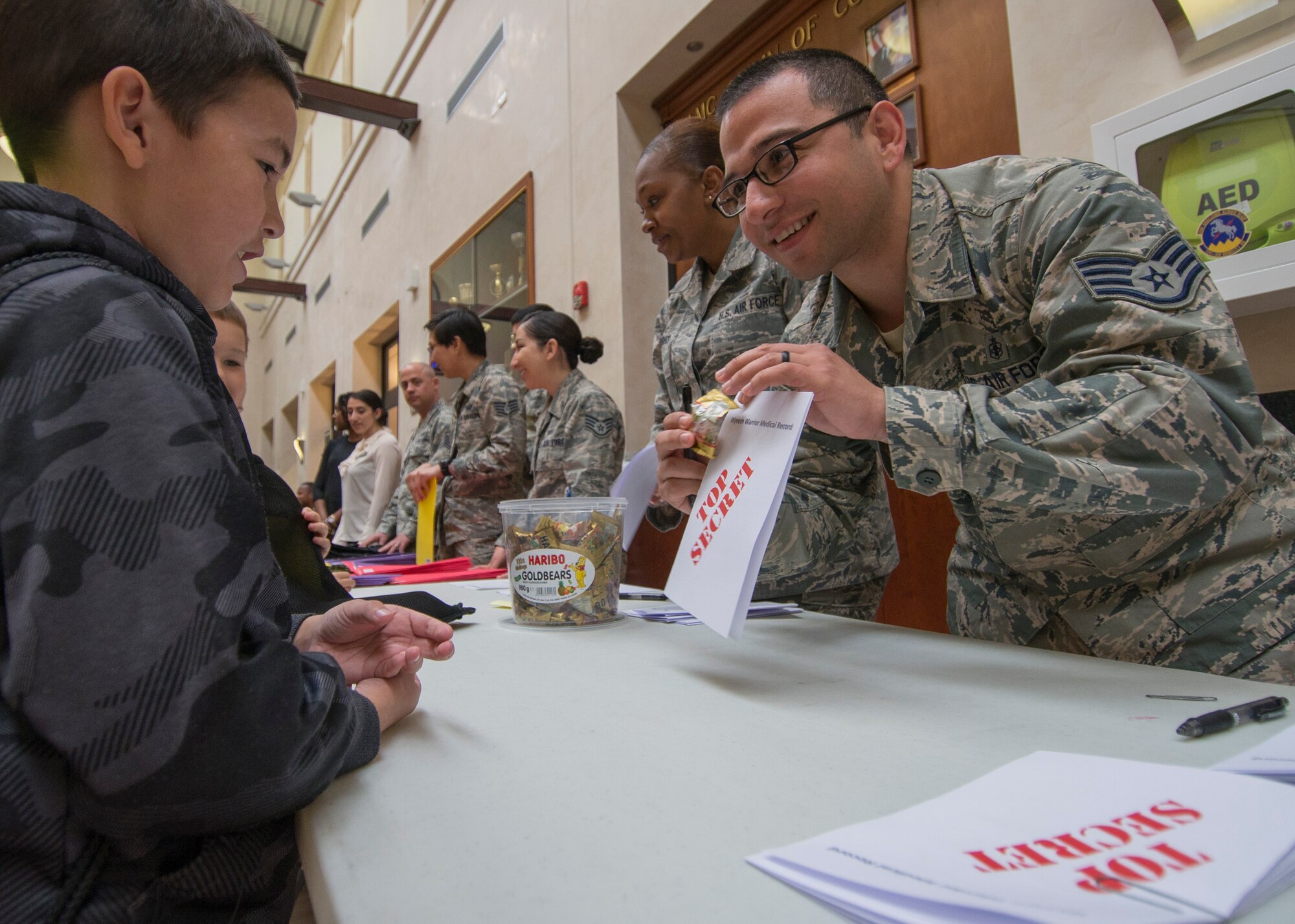 Staff Sgt. Salvador Gutierrez, 31st Aerospace Medicine Squadron NCO in charge of communicable diseases, gives an Aviano Elementary School student his mock medical records during a Little Wyvern Warriors deployment line May 5, 2016, at Aviano Air Base, Italy. The event gave children a firsthand look at the preparation needed for a deployment, viewed components of an F-16 Fighting Falcon and base agency displays. (U.S. Air Force photo by Airman 1st Class Cory W. Bush/Released)