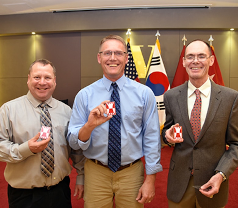 Col. Philip A. Keller, Col. Michael D. Nyenhuis and Lt. Col. Mitchell A. DeMarais were honored at a hosted dinner on Friday, April 22, 2016, which was presided over by Maj. Gen. James T. Walton, director of USFK Transformation and Restationing. Here, the three retiring officers pose with a commander's coin from a now-disbanded Reserve unit they had all once belonged to; the three have combined more than 90 years of military service.