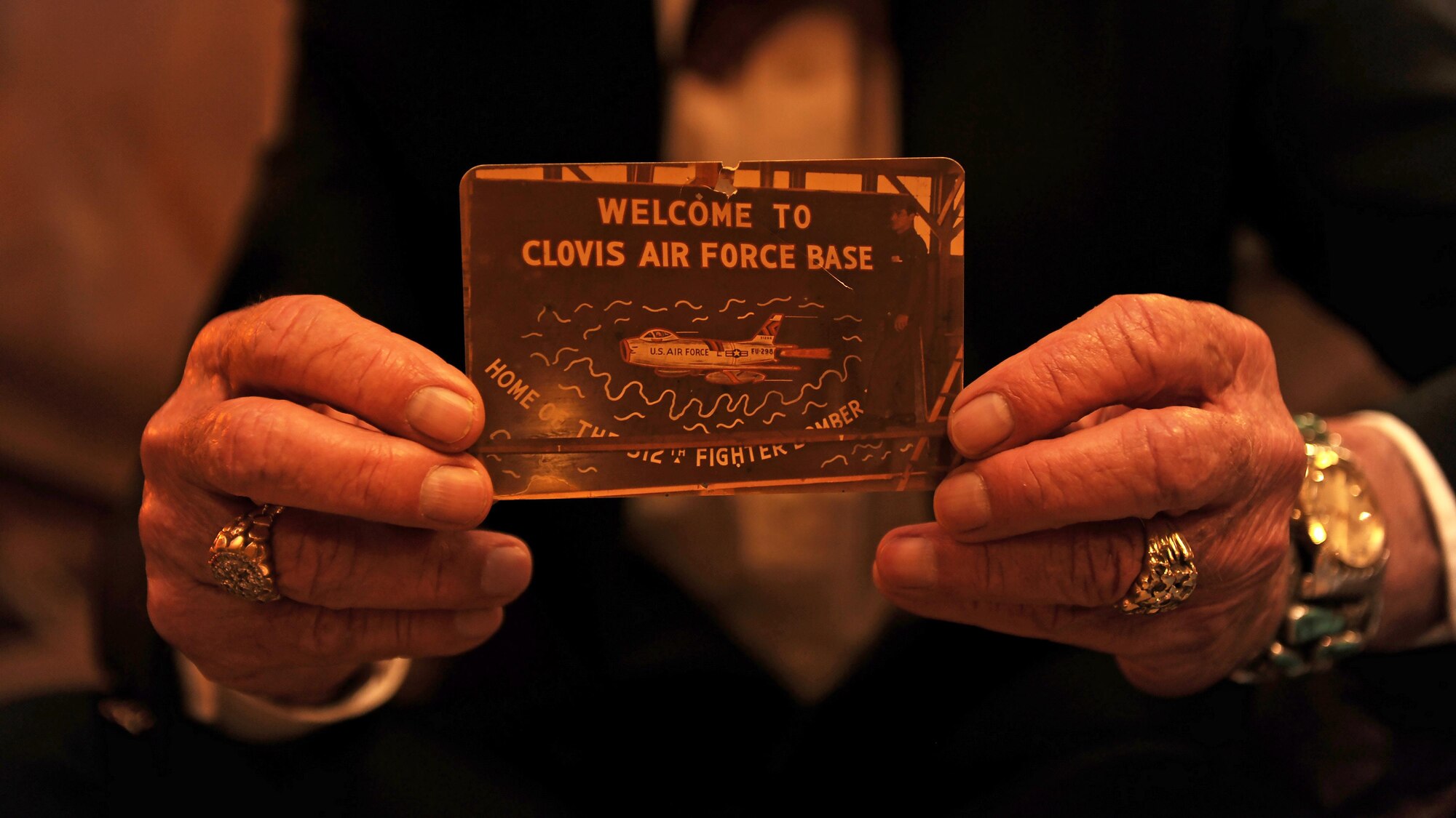 Chuck Hager, former Airman, holds a photo of himself painting the ‘Welcome to Clovis Air Force Base’ sign at a local coffee house April 19, 2016, in Clovis, N.M. The welcome sign, which used to be mounted at the base’s main gate, was repainted by Hager in 1957 when the base was renamed as Cannon Air Force Base. (U.S. Air Force photo/Staff Sgt. Whitney Amstutz)
