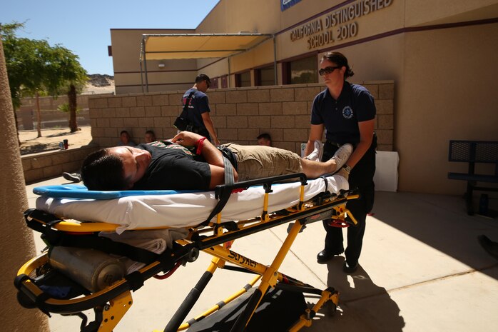 Becky Marx, a reserve emergency medical technician, transports a role player to an ambulance during an active shooter exercise at Marine Corps Air Ground Combat Center, Twentynine Palms, California. The Marine Corps is the first service to standardize E911 capabilities. The Consolidated Emergency Response Systems Program is implementing a product suite used across the nation by emergency dispatchers to locate the caller’s location on a graphical display by GPS, thus increasing response time. (U.S. Marine Corps photo by Cpl. Charles Santamaria)
