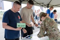 First Sgt. Robert Dicks, the first sergeant for Operations Company, Headquarters and Headquarters Battalion, 101st Airborne Division (Air Assault), and Capt. Marc Eskew, commander of Ops. Co., pick up their numbers from Spc. Abigail Schiltz, a personnel and administration specialist for the 101st, before the Kurdish Training Coordination Center Survival Fun Run held near Erbil, Iraq, May 6, 2016. The Morale, Welfare and Recreation event consisted of the choice between a 5-, 10- or 15-kilometer route with obstacles spread throughout and allowed Soldiers to have fun and build camaraderie with their peers. (U.S. Army Photo by Staff Sgt. Peter J. Berardi)