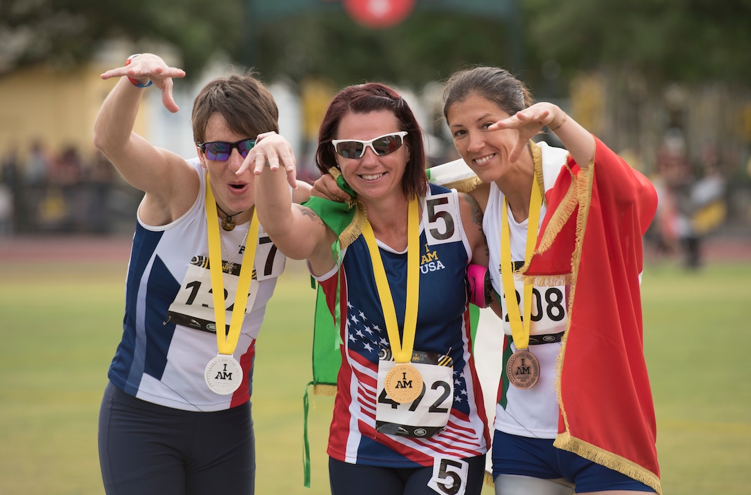 Marine Corps veteran Sarah Rudder, center, a women's 100-meter gold medalist, celebrates with France's Marion Blot, left, the silver medalist, and Italy's Monica Contrafatto, the bronze medalist, right, during the 2016 Invictus Games in Orlando, Fla., May 10, 2016. DoD photo by Roger Wollenberg