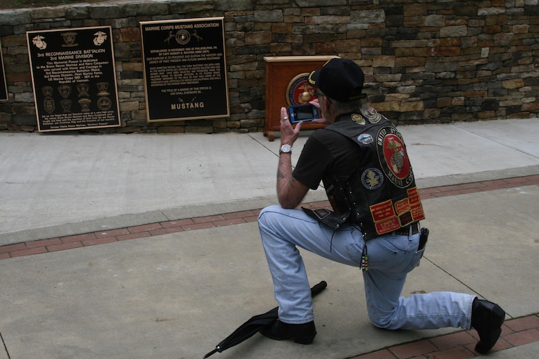 A veteran from the 3rd Reconnaissance Battalion takes a souvenir photo of the commemorative plaque dedicated to the memory and valor of his unit for its mission and time in Southeast Asia during the Vietnam War.