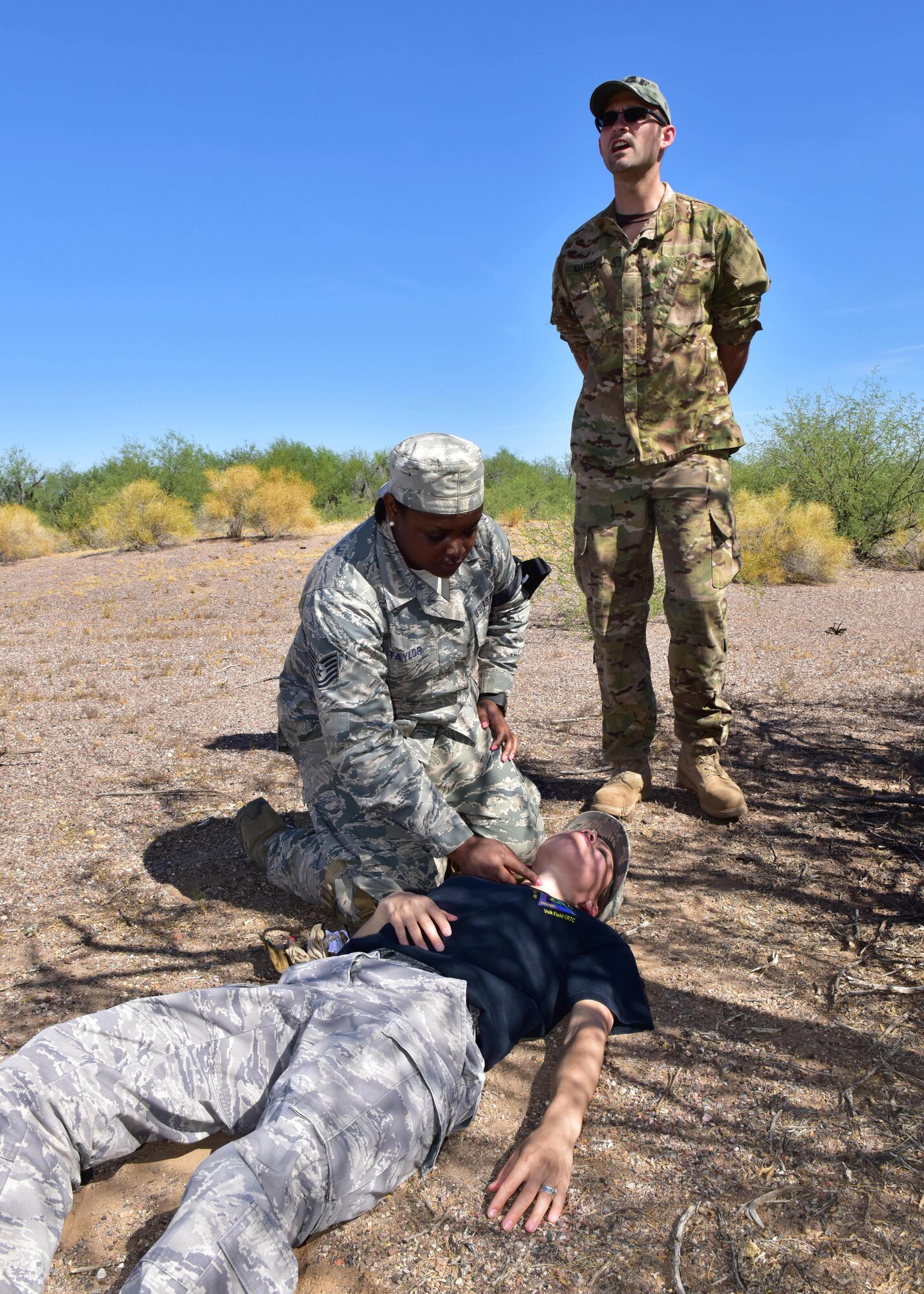 Tech. Sgt. Tiesha Taylor, 403rd Aeromedical Staging Squadron medical technician, provides medical care to Senior Master Sgt. Katherine Soehnen, 944th ASTS assistant superintendent and simulation patient, while Master Sgt. Christopher Martin, 944th ASTS NCO in charge of Joint Military Operations Training Initiative (JMOTI) during a Tactical Combat Casualty Care (TCCC) training exercise at Luke Air Force Base Auxiliary Field 1, Ariz. (U.S. Air Force photo by Tech. Sgt. Louis Vega Jr.)