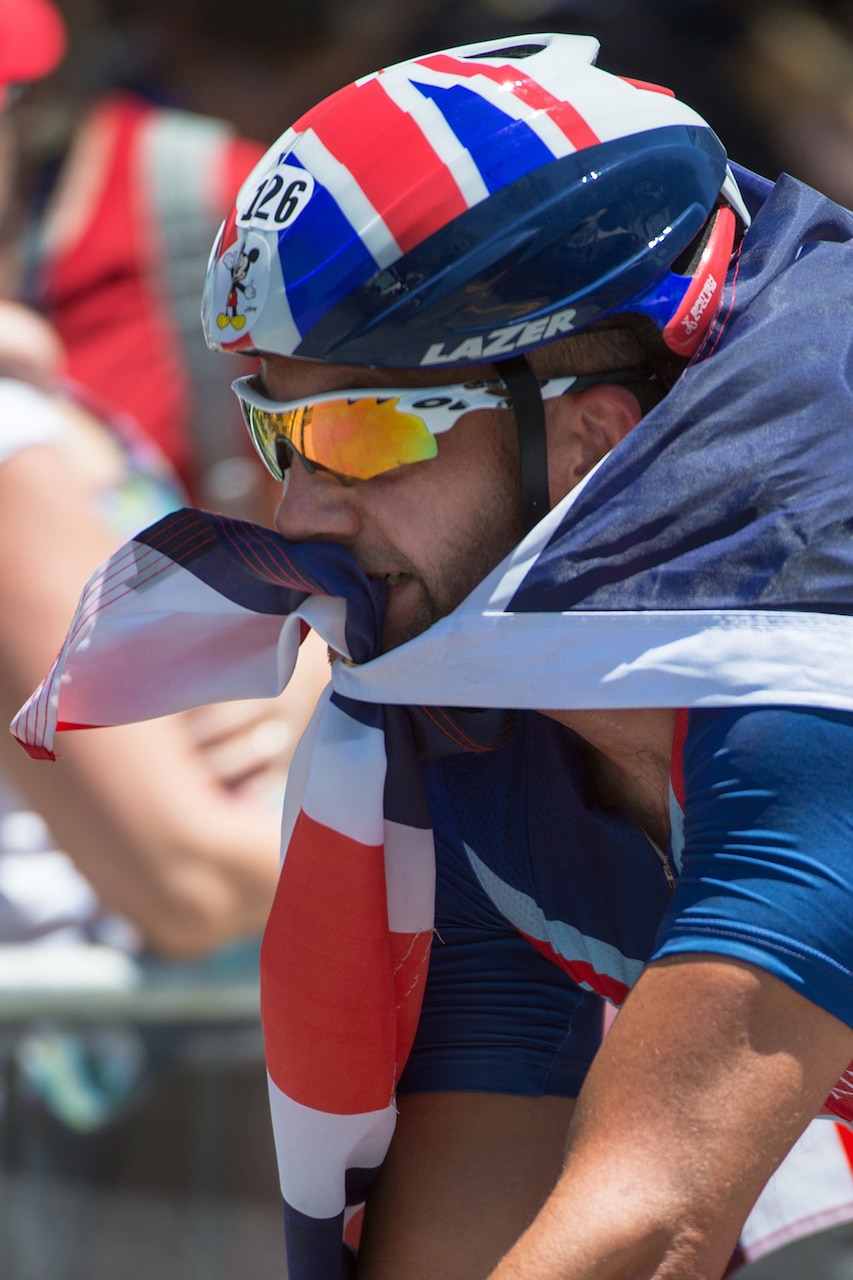 Great Britain’s Michael Westwall carries a flag in his mouth after winning a cycling event during the 2016 Invictus Games in Orlando, Fla., May 9, 2016. DoD photo by EJ Hersom