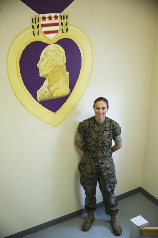 Lance Cpl. Ashley Tichensky, a motor-transportation operator with Transportation Services Company, Combat Logistics Battalion 2, poses beside her Purple Heart Medal painting at the battalion headquarters building at Camp Lejeune, N.C., May 5, 2016. In the past month, Tichensky spent roughly 15 hours drawing and painting a replica of the medal to represent her battalion’s Marines who have been awarded this military decoration during their service. (U.S. Marine Corps photo by Cpl. Kaitlyn V. Klein/Released)