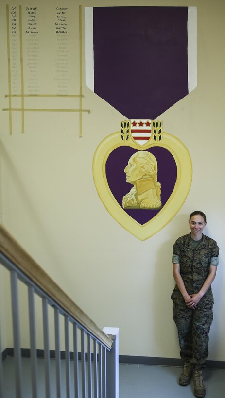 Lance Cpl. Ashley Tichensky, a motor-transportation operator with Transportation Services Company, Combat Logistics Battalion 2, poses beside her Purple Heart Medal painting at the battalion headquarters building at Camp Lejeune, N.C., May 5, 2016. During the past month, Tichensky spent roughly 15 hours drawing and painting a replica of the medal to represent her battalion’s Marines who have been awarded this military decoration during their service. (U.S. Marine Corps photo by Cpl. Kaitlyn V. Klein/Released)