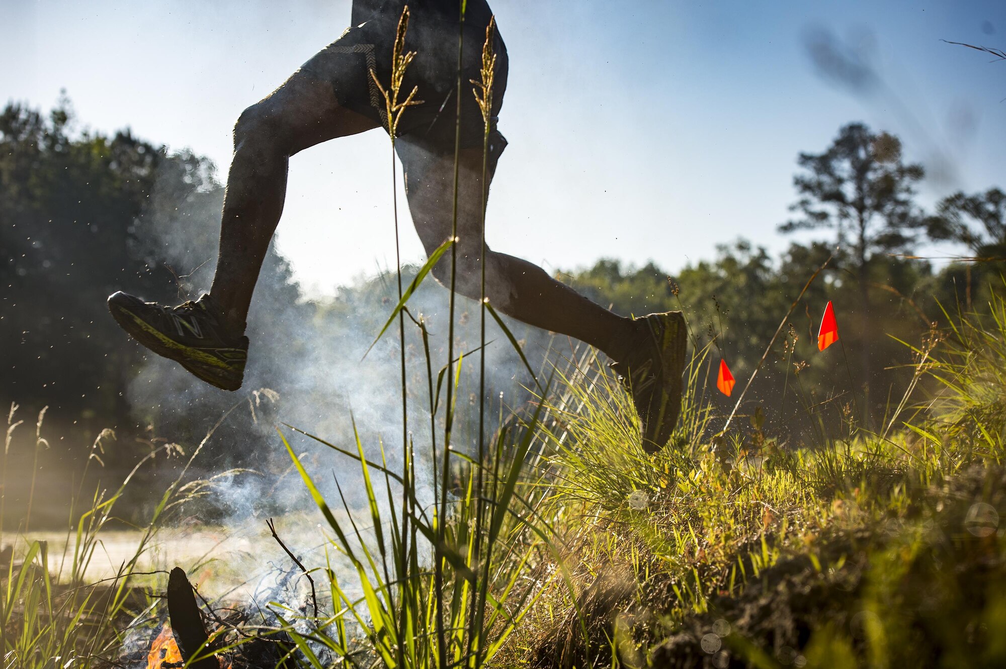 A runner jumps over a fire during the 2016 Moody Mudder, May 7, 2016, in Ray City, Ga. The Mudder challenged nearly 500 competitors to complete 20 obstacles on a 3.12-mile course for the third year in a row. (U.S. Air Force photo by Senior Airman Ryan Callaghan/Released)