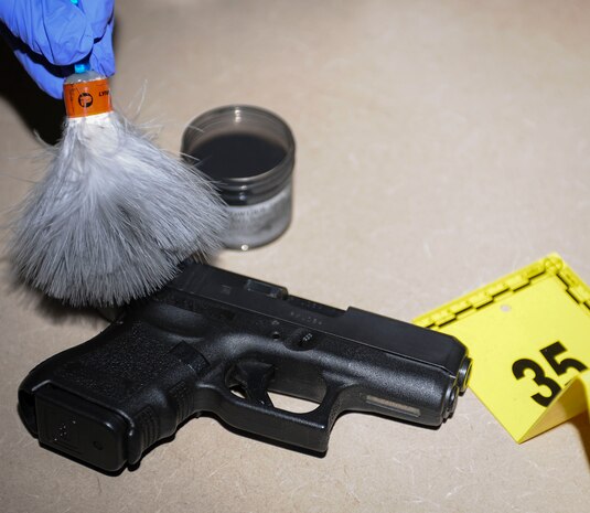 160429-F-UN699-048: Special Agent Ashley Rivera, Air Force Office of Special Investigations detachment 206, criminal investigator, dusts a handgun for fingerprints May 2, 2016 at Nellis Air Force Base, Nev. For 2015, det. 206 was recognized as the best large Air Force OSI detachment after saving the Air Force millions of dollars. (U.S. Air Force photo by Senior Airman Jake Carter)