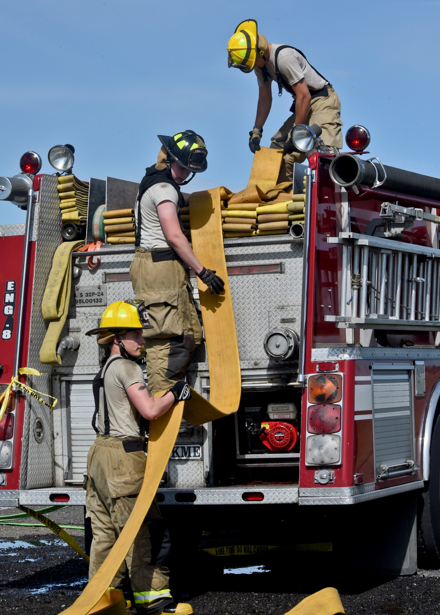 Senior Airman Logan Crytzer (bottom), 92nd Civil Engineer Squadron firefighter, Senior Airman Aaron Menhart (middle), 92nd CES firefighter, and Airman 1st Class Jordan Davis (top), 92nd CES firefighter, work together to put away one of the fire hoses after a training exercise May 11, 2016, at Fairchild Air Force Base, Wash. The crews responded to a simulated aircraft crash where an F-18 had mechanical issues and hit a nearby structure. “I found this exercise very helpful,” said Menhart. “I was able to practice a scenario we don’t do very often. This is a realistic emergency that could happen at any time. It’s important to train and be ready for that moment.” (U.S. Air Force photo/Airman 1st Class Taylor Bourgeous)