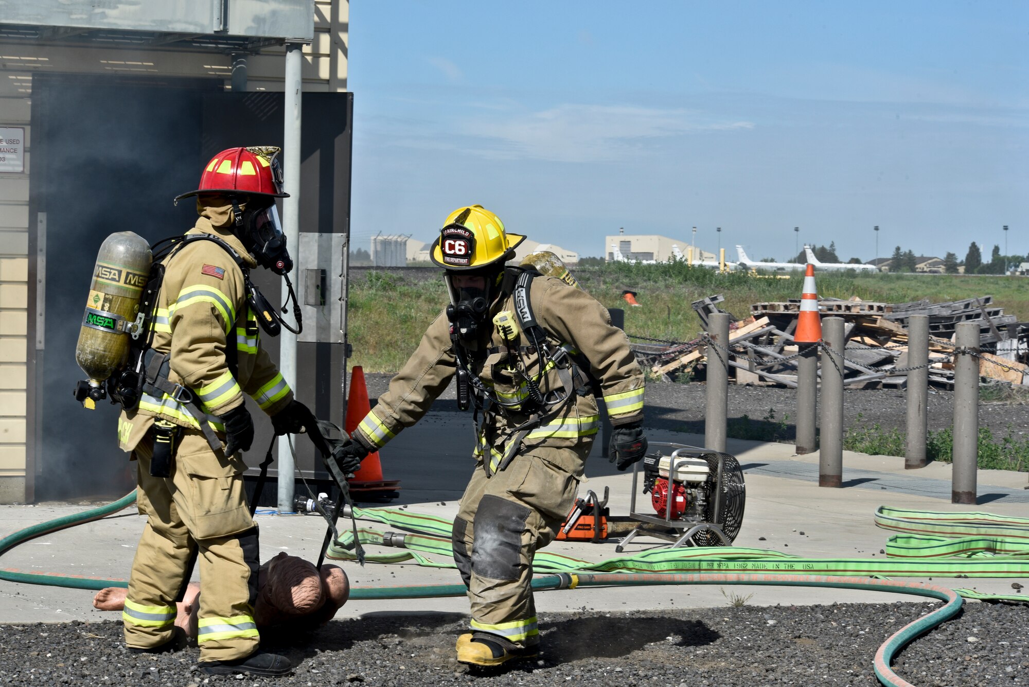 92nd Civil Engineer Squadron firefighters pull out a mannequin from the simulated structure fire during a training exercise May 11, 2016, at Fairchild Air Force Base, Wash. During the exercise the firefighters reacted to a structure fire and simulated the rescue of two victims. (U.S. Air Force photo/Airman 1st Class Taylor Bourgeous)