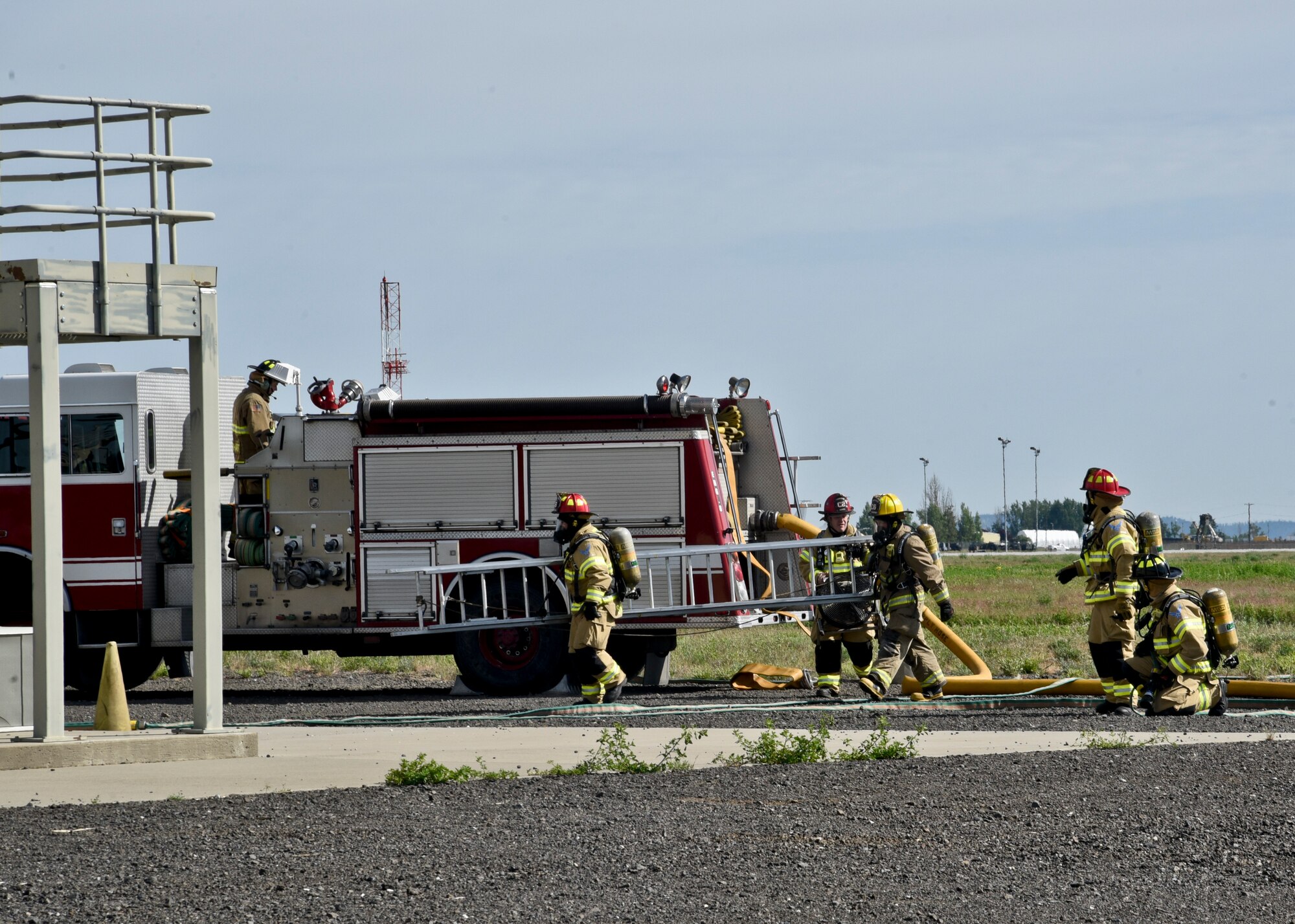 Firefighters from the 92nd Civil Engineer Squadron bring a ladder to a mock structure fire May 11, 2016, at Fairchild Air Force Base, Wash. The crews responded to a simulated aircraft crash where an F-18 experienced various mechanical issues and clipped a nearby structure. During the descent, the pilot was forced to drop armament and then eject. (U.S. Air Force photo/Airman 1st Class Taylor Bourgeous)