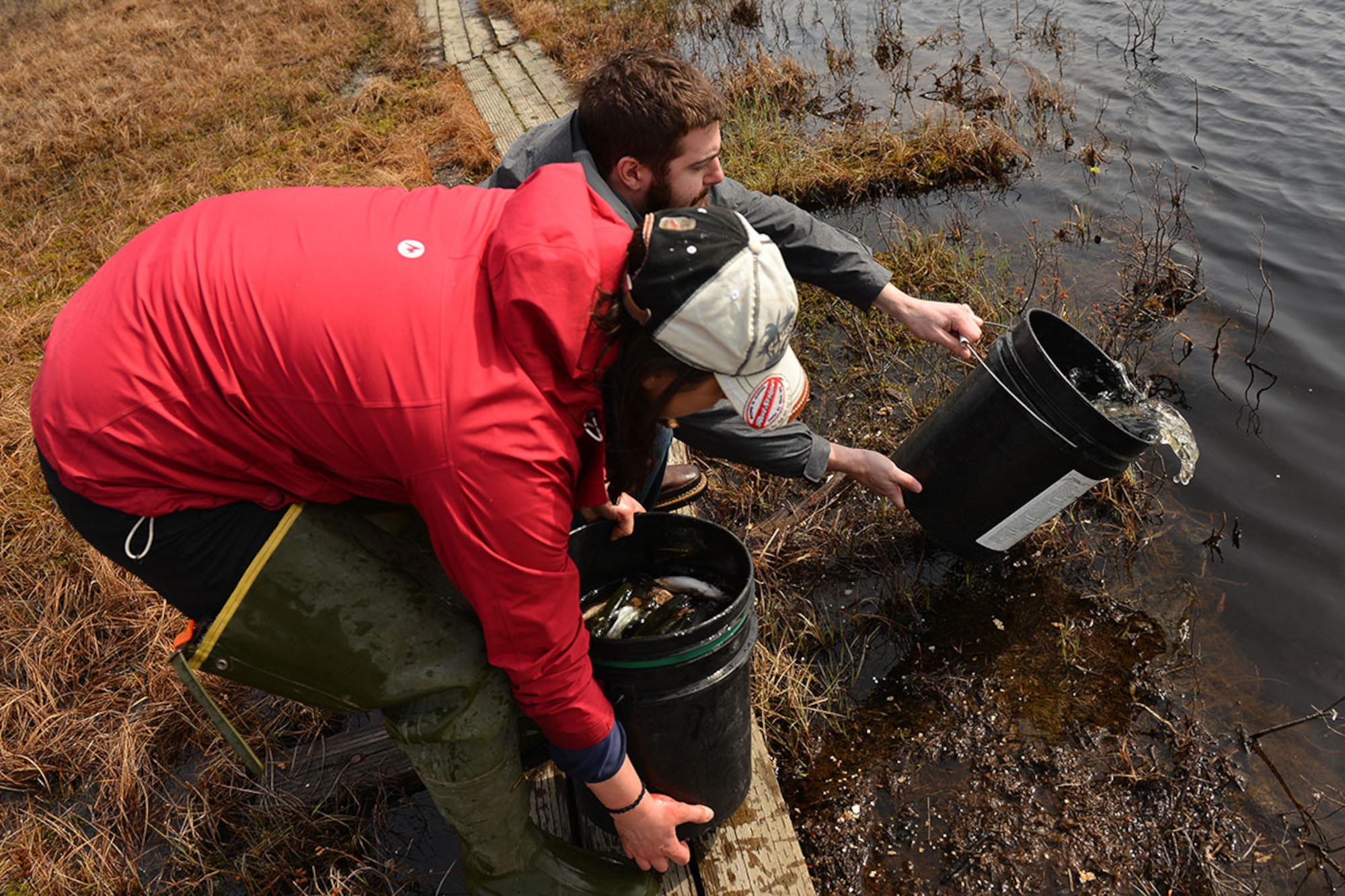 Krystina Bottom, fisheries crew lead with the Center for Environmental Management of Military Lands, and Sam Satre, a fisheries technician with the CEMML, empty buckets of rainbow trout into Fish Lake May 9. Depending on the location, the technicians will either transport the fish manually by bucket, or pump them through a tube from the truck directly. (U.S. Air Force photo by Senior Airman Kyle Johnson)