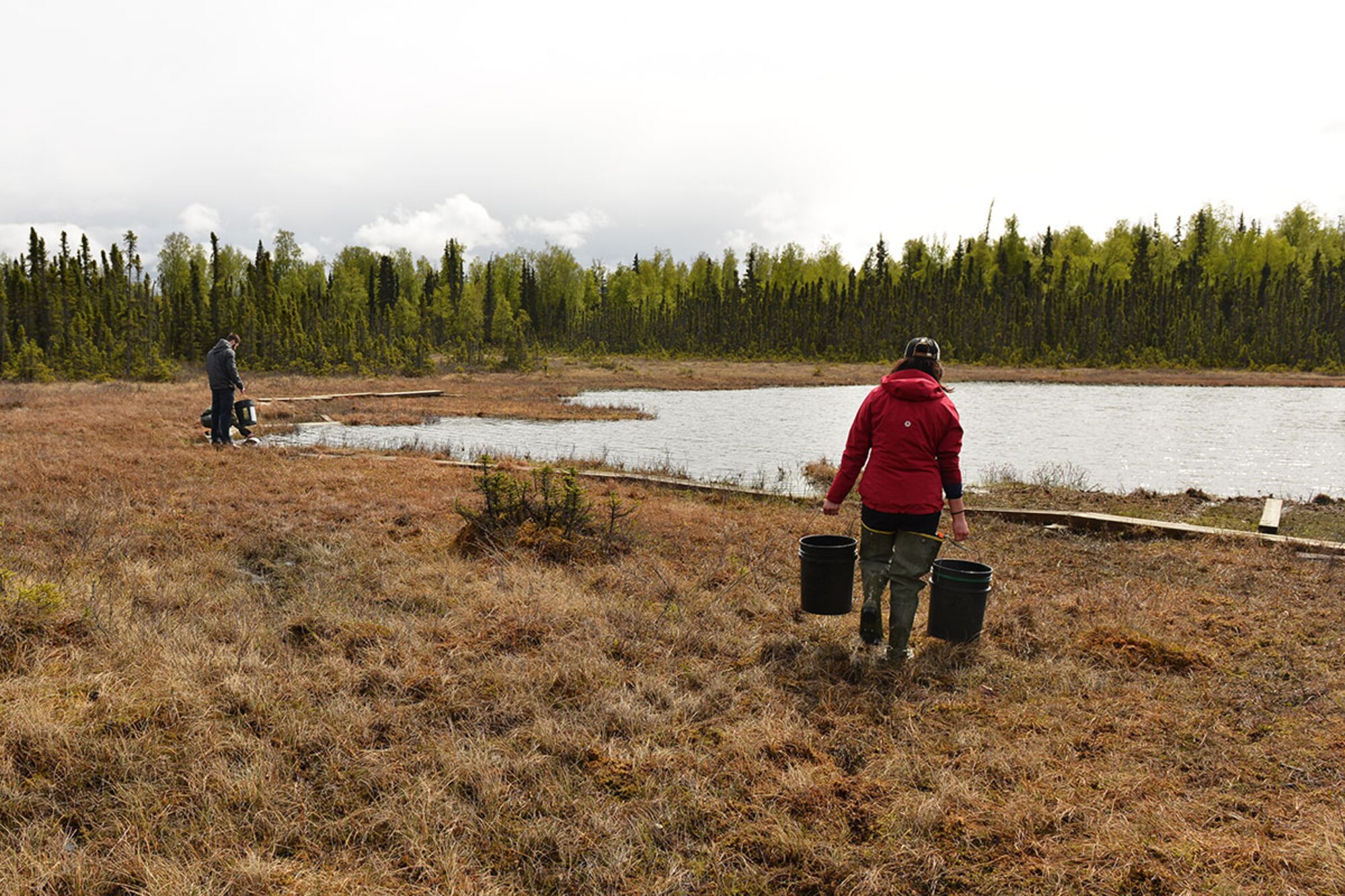 Krystina Bottom, fisheries crew lead with the Center for Environmental Management of Military Lands takes two buckets of rainbow trout to the shore of Fish Lake May 9. Depending on the location, the technicians will either transport the fish manually by bucket, or pump them through a tube from the truck directly. (U.S. Air Force photo by Senior Airman Kyle Johnson)