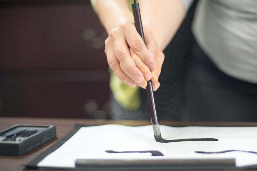 Attendees write Japanese calligraphy during the Military Spouse Appreciation Day at Yokota Air Base, Japan, May 6, 2016. The Airman and Family Readiness Center hosted the event which included a calligraphy class, tea ceremony and a musical performance. (U.S. Air Force photo by Senior Airman David C. Danford/Released)
