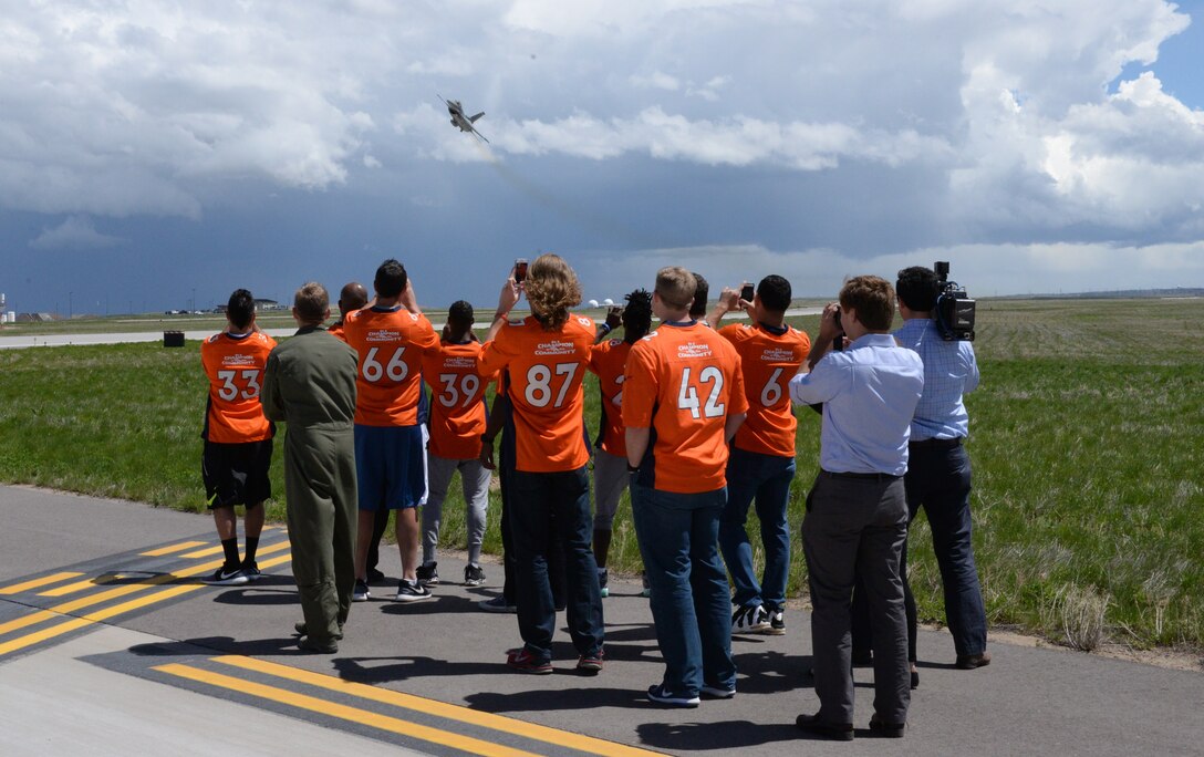 Several members of the Denver Broncos watch as an F-16 Fighting Falcon aircraft, flown by the 120th Fighter Squadron, 140th Wing, Colorado Air National Guard, flies overhead during their visit to Buckley Air Force Base May 10. The 140th Wing provides F-16 flyovers for Bronco games whenever authorized and several of the athletes came to see the Airmen who help make it possible. (U.S. Air National Guard photo by Senior Master Sgt. John Rohrer)