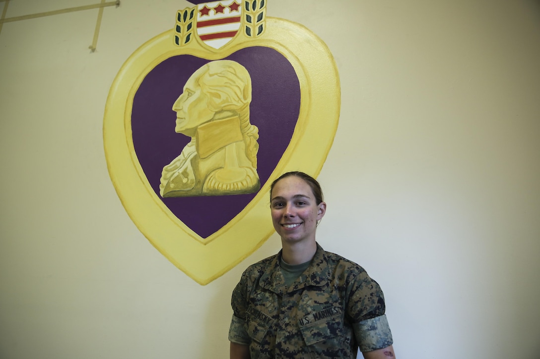 Lance Cpl. Ashley Tichensky, a motor-transportation operator with Transportation Services Company, Combat Logistics Battalion 2, poses beside her Purple Heart Medal painting at the battalion headquarters building at Camp Lejeune, N.C., May 5, 2016. During the past month, Tichensky spent roughly 15 hours drawing and painting a replica of the medal to represent her battalion’s Marines who have been awarded this military decoration during their service. (U.S. Marine Corps photo by Cpl. Kaitlyn V. Klein/Released)