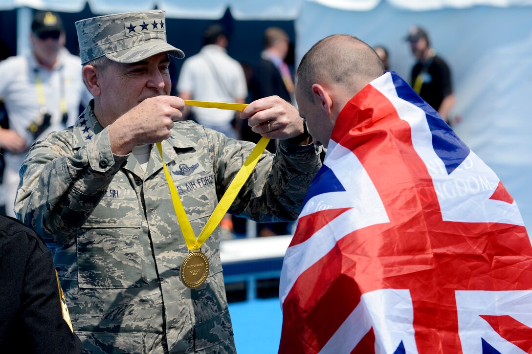 U.S. Air Force Gen. Mark A. Welsh III, left, presents the gold medal to a British swimmer at the 2016 Invictus Games in Orlando, Fla., May 11, 2016. Air Force photo by Staff Sgt. Carlin Leslie