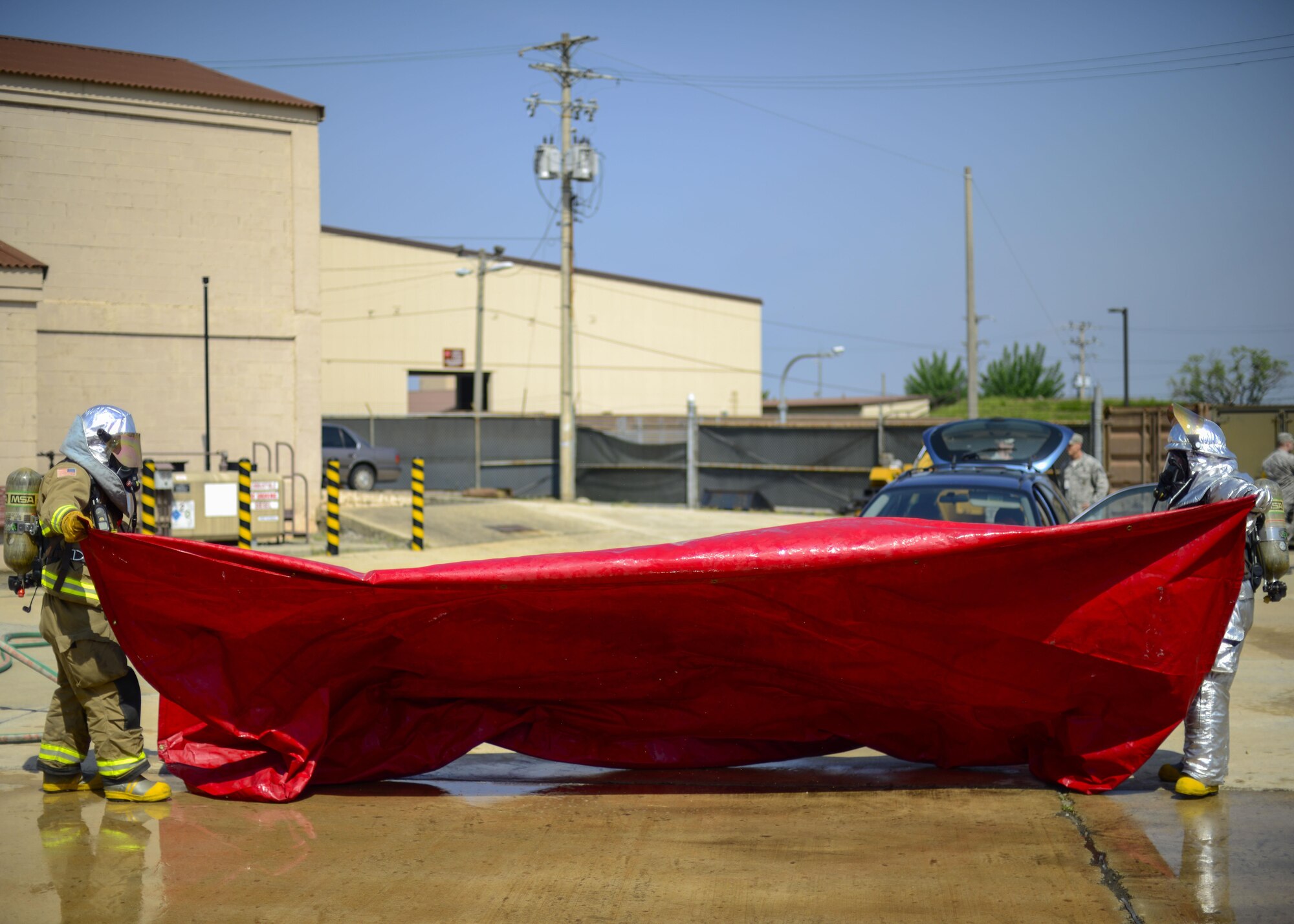 Firefighters assigned to the 51st Civil Engineer Squadron unfold a salvage cover during Exercise Beverly Herd 16-01 at Osan Air Base, Republic of Korea, May 12, 2016. The firefighters simulated putting a vehicle fire out and used the cover to help contain any possible contaminants after the fire was extinguished. (U.S. Air Force photo by Senior Airman Victor J. Caputo/Released)