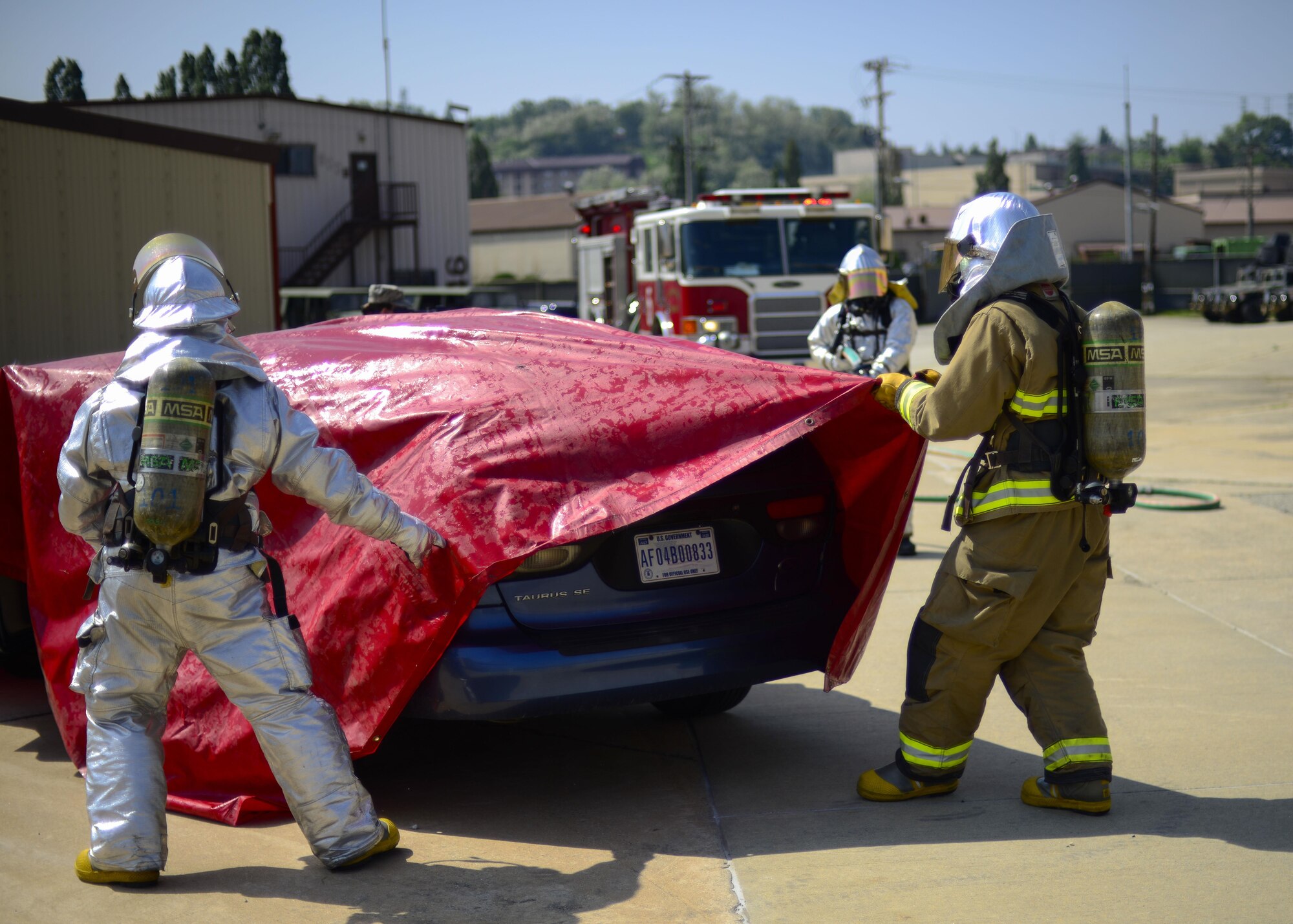 Firefighters assigned to the 51st Civil Engineer Squadron pull a tarp over a vehicle during Exercise Beverly Herd 16-01 at Osan Air Base, Republic of Korea, May 12, 2016. The vehicle was used to simulate a vehicle fire after a mock improvised explosive device was detonated, and the firefighters used the cover to help contain any possible contaminants after the fire was extinguished. (U.S. Air Force photo by Senior Airman Victor J. Caputo/Released)