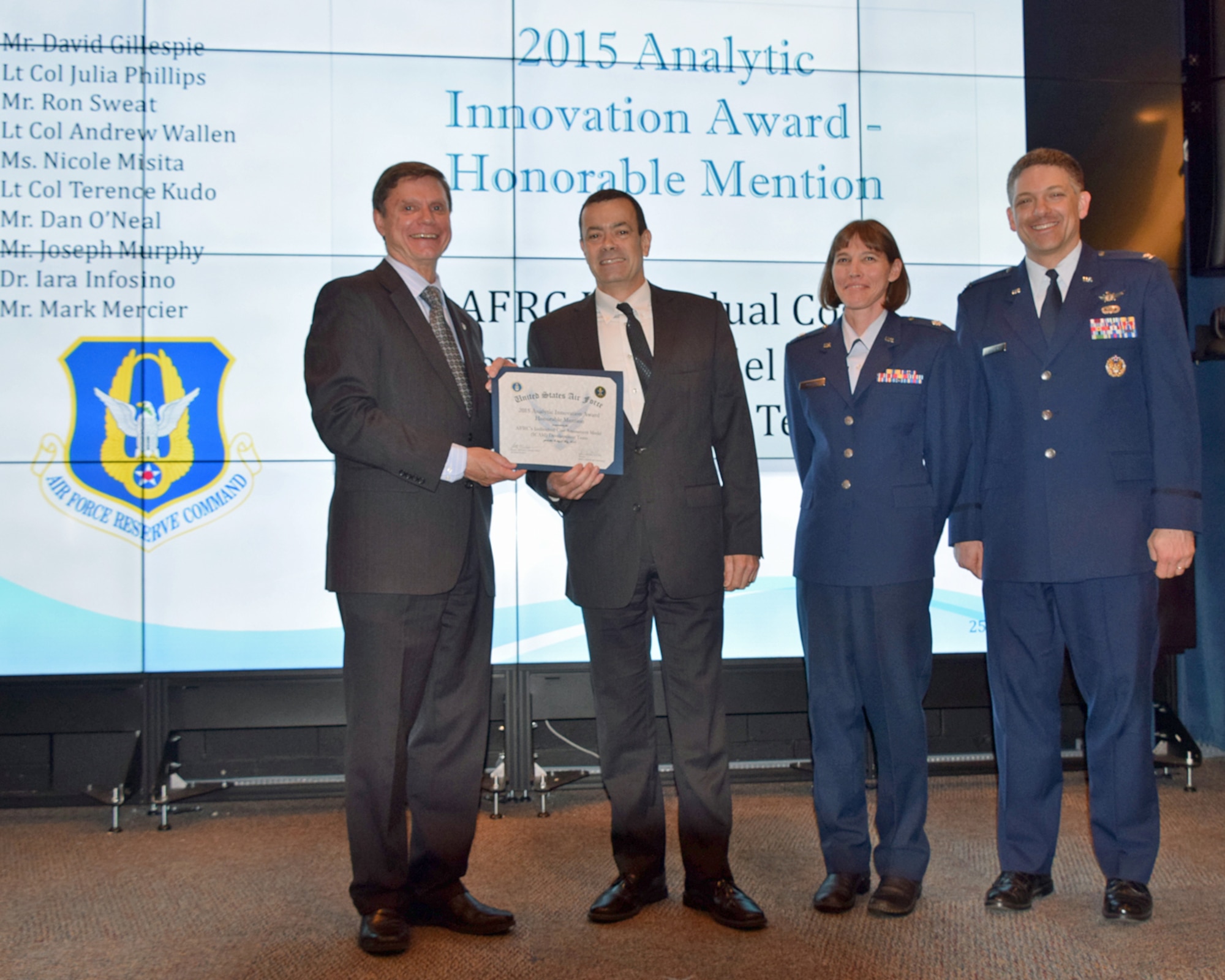 Kevin Williams, director of Air Force A9 Studies, Analyses and Assessments (left) presents the Air Force Analytic Innovation Honorable Mention Award to David Gillespie and Lt. Col. Julia Phillips from Air Force Reserve Command's Individual Cost Assessment Model team, while Col. Scott Williams, Air Force chief analyst, looks on during a ceremony at the Air Force Institute of Technology,Wright-Patterson AFB, Ohio, May 4.