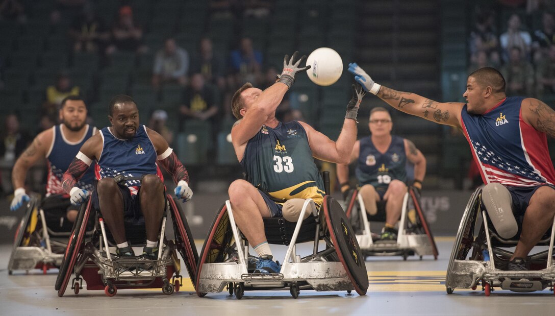 Marine Corps veteran Alex Nguyen reaches for the ball during a semifinal wheelchair rugby match at the 2016 Invictus Games in Orlando, Fla., May 11, 2016. Also pictured are Marine Corps veteran Jorge Salazar, left, and Navy veteran Henry Sawyer, left center. DoD photo by Roger Wollenberg