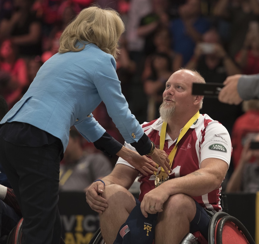 Dr. Jill Biden presents a gold medal to Air Force veteran Tim Wymore after the U.S. defeated Denmark in their wheelchair rugby finals match during the 2016 Invictus Games in Orlando, Fla., May 11, 2016. DoD photo by Roger Wollenberg