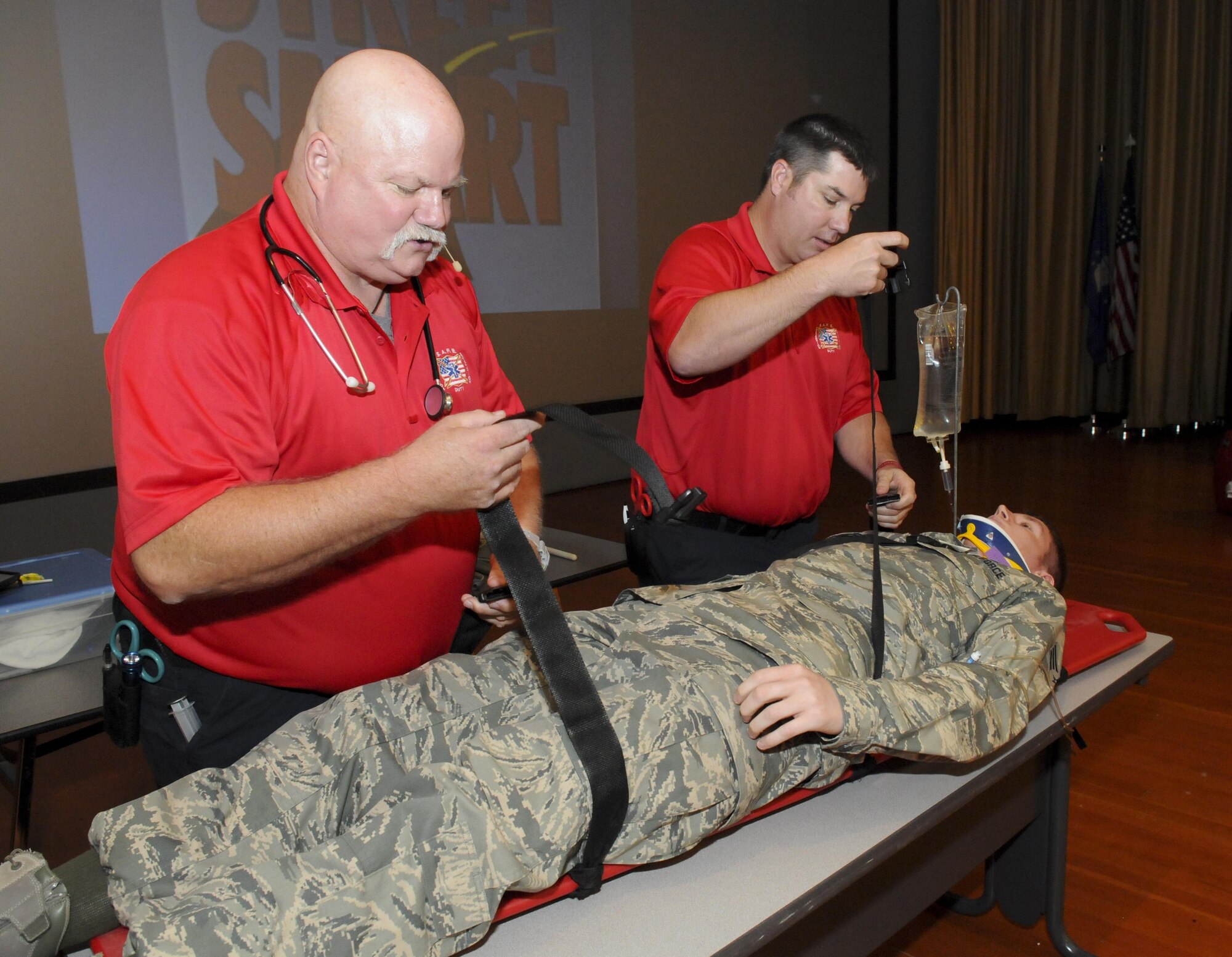 Greg McCarty (Left) and David Dittman (Right) Florida Stay Alive From Education (S.A.F.E.) Inc. presenters, fasten SrA Newton Chapman, 9th Aircraft Maintenance Squadron network management technician, to a stretcher at Independence Hall on Beale Air Force Base, California, May 11, 2016. Chapman was part of a simulated car wreck during the Tragedy Can be Avoided event. (U.S. Air Force photo by Senior Airman Michael J. Hunsaker)