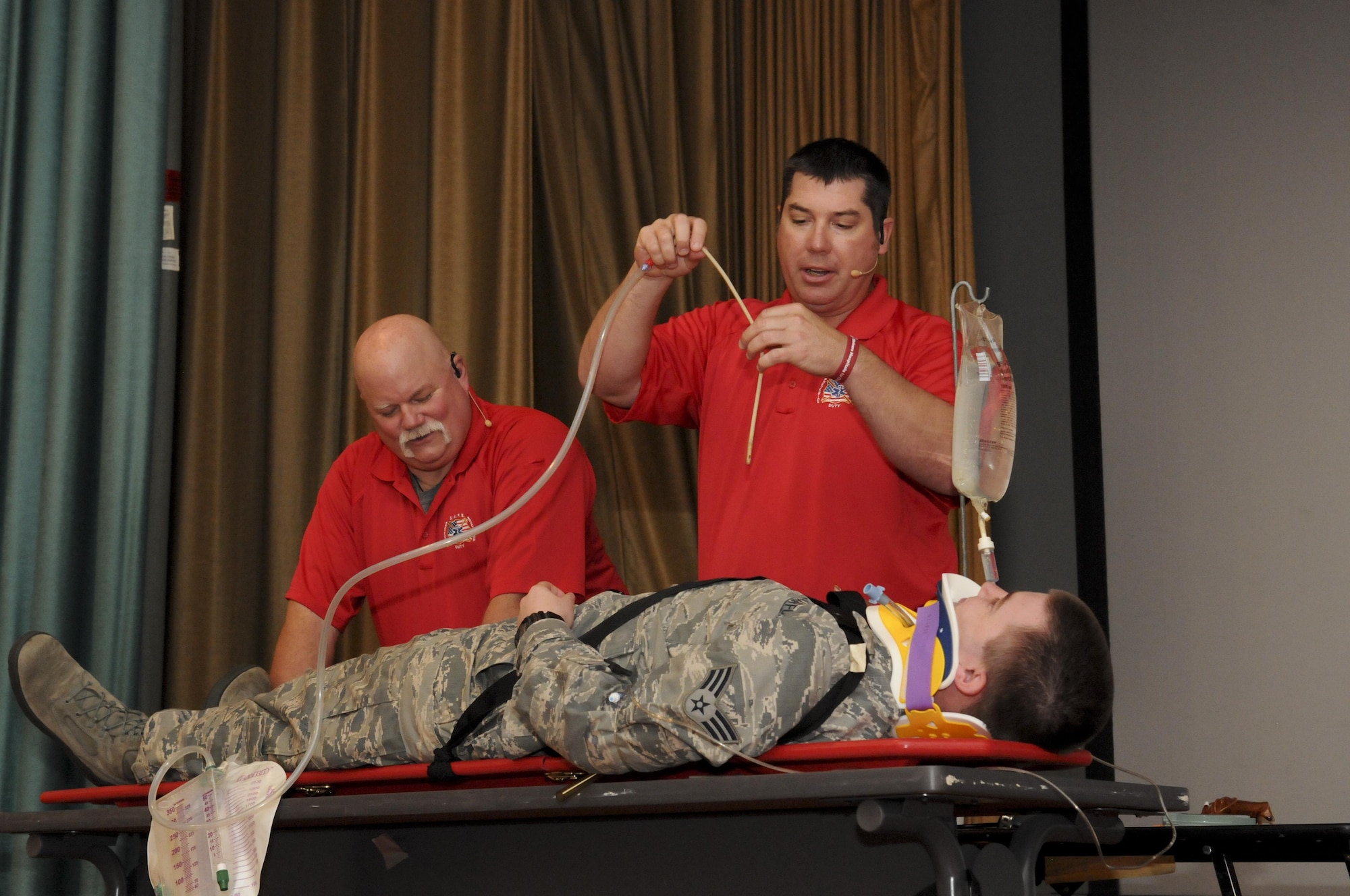 Greg McCarty (Right) and David Dittman (Top) Florida Stay Alive From Education (S.A.F.E.) Inc. presenters, perform a simulated medical examination of SrA Newton Chapman (Center) and SrA David Van Winkle (Left), 9th Aircraft Maintenance Squadron network management technicians, at Independence Hall on Beale Air Force Base, California, May 11, 2016. Chapman and Van Winkle were part of a simulated car wreck during the Tragedy Can be Avoided event. (U.S. Air Force photo by Senior Airman Michael J. Hunsaker)