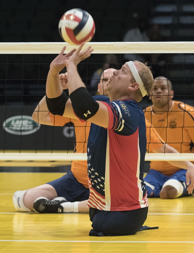 Marine Corps veteran Travis Greene sets the ball for a team member to spike in a sitting volleyball semifinals match at the 2016 Invictus Games in Orlando, Fla., May 11, 2016. DoD photo by Roger Wollenberg