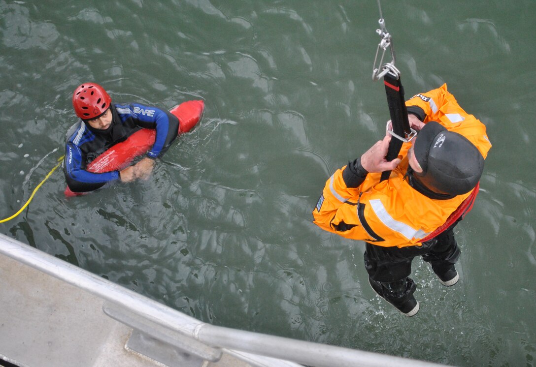Steve Rohner, right, a crewmember of the M/V John A. B. Dillard, Jr., holds on as he is raised out of the water by a mechanized davit system May 5, while Miguel Nieto watches on. The Dillard crew conducted three days of rescue swimmer training in the San Francisco Bay May 3-5.  