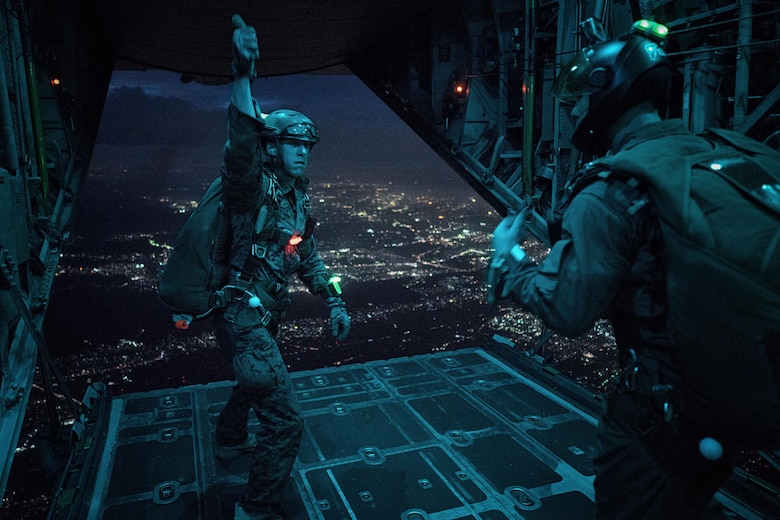 A Marine with the 3rd Reconnaissance Battalion, 3rd Marine Division, III Marine Expeditionary Force, uses hand signals to communicate with fellow Marine jumpers in a C-130 Hercules over Yokota Air Base, Japan, May 11, 2016. The Marines were conducting a night jump as part of their yearly jump currency. (U.S. Air Force photo by Senior Airman Delano Scott/Released)