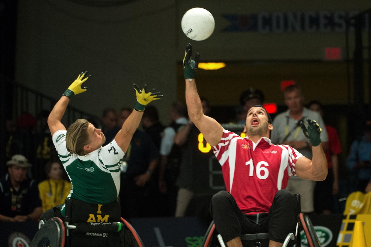 New York Jets wide receiver Eric Decker, right, and Emmy award-winning dancer and actor Derek Hough reach for a ball during a wheelchair rugby exhibition match in association with the 2016 Invictus Games in Orlando, Fla., May 11, 2016. DoD photo by EJ Hersom
