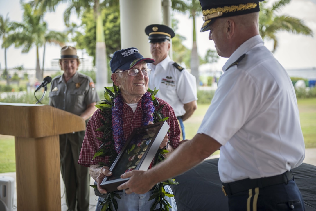 Charles Wolf, a World War ll veteran is presented with medals by Brig. Gen. Mark Spindler, Deputy Director of the Defense POW/MIA Accounting Agency (DPAA) at the Pearl Harbor Education Center, Hawaii, May 6, 2016. After 72 years, Wolf was finally awarded his numerous medals and awards for his selfless service to this nation. A surprise ceremony was held in Wolf's honor, where family and visitors watched as Spindler presented him his shadow box. DPAA's mission is to provide the fullest possible accounting for our missing personnel to their families and the nation. (DoD photo by MC2 Aiyana Paschal/RELEASED)  
