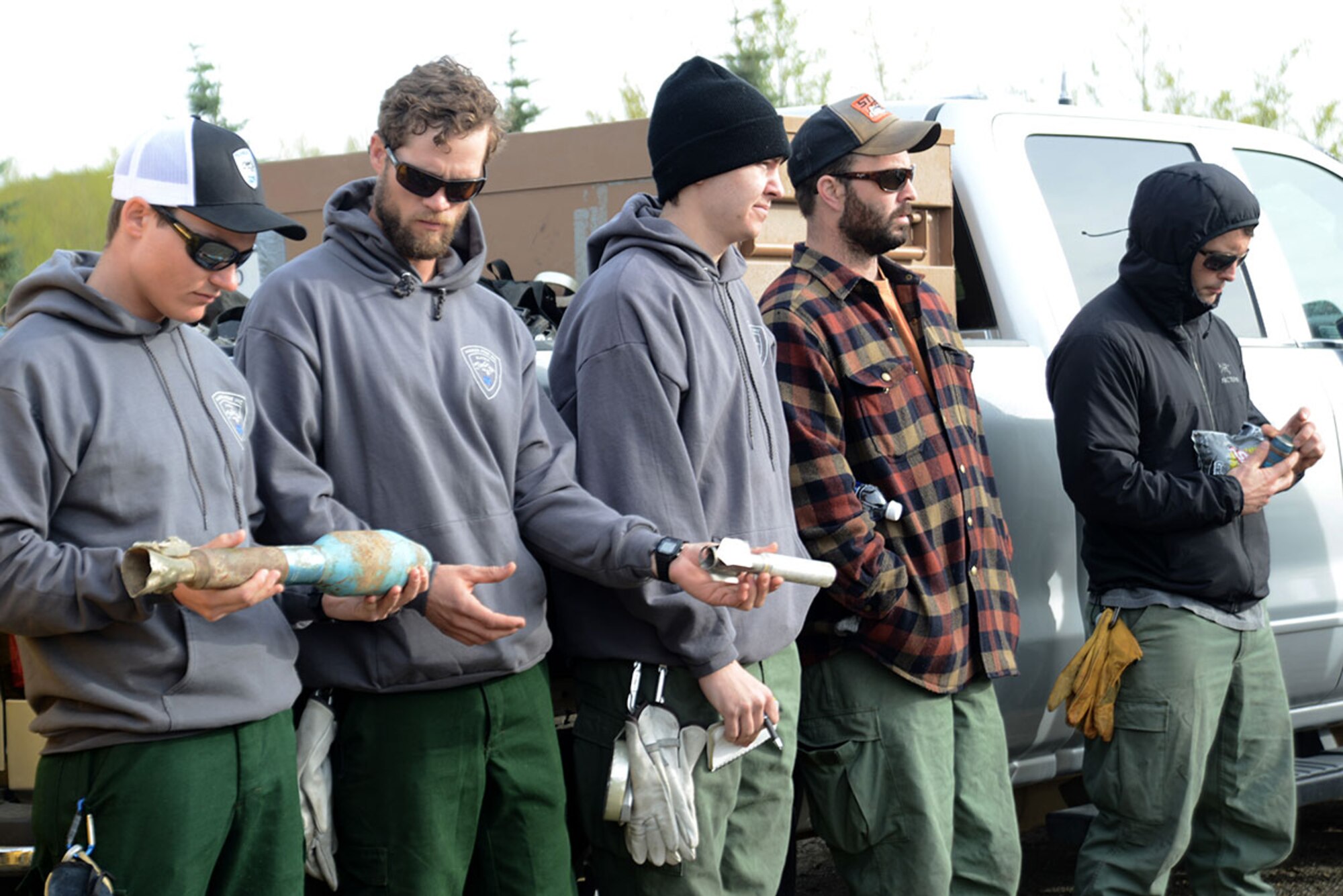 Members from the Alaska Division of Forestry and Joint Base Elmendorf-Richardson Fire Department pass around inert ordinance so they know what to look out for on the range during the prescribed burns at Grezelka range, Alaska, May 2, 2016. According to the National Oceanic and Atmospheric Administration, last winter in Alaska was the second warmest on record dating back to 1925. Combined with record-low snowfall and precipitation, the chance of fire activity greatly increases as combustible dry detritus accumulates. Controlled burns reduce the chance of spot fires by removing excess dry brush and grass. (U.S. Air Force photo by Airman 1st Class Christopher R. Morales)