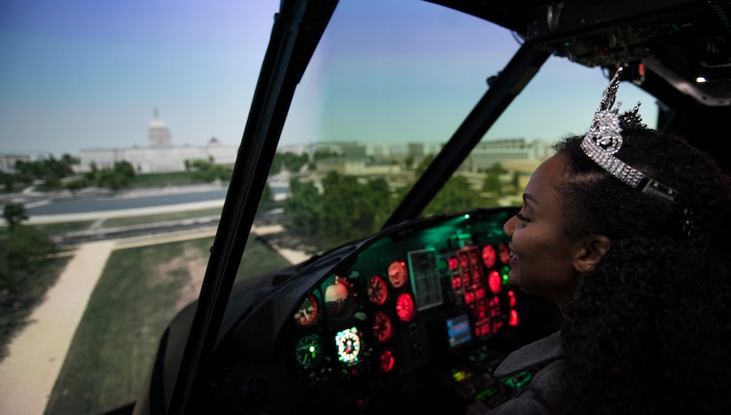 Kinosha Soden, Mrs. DC America and military spouse, sits in a 1st Helicopter Squadron flight simulator during a base tour at Joint Base Andrews, Md., May 11, 2016. Soden toured the base to familiarize herself with the operations and mission of the base. (U.S. Air Force photo by Airman 1st Class Philip Bryant) 