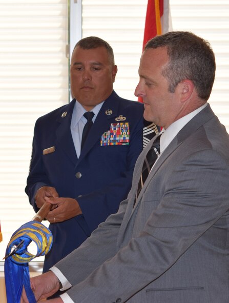 Robert Kraus, the new F-35 Partner Support Complex director, unfurls unit's guidon during an activation ceremony May 11, at Eglin Air Force Base, Fla. The F-35 PSC will provide mission data, intelligence support, lab facilities, and training to the eight partner countries purchasing the F-35 Lightning II aircraft. (U.S. Air Force Photo by 1st Lt. Amanda Farr)