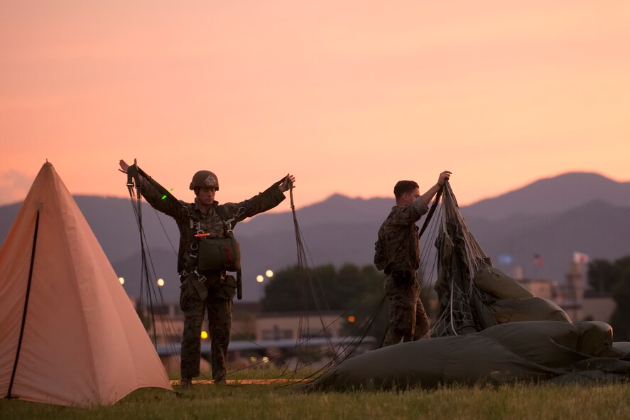 U.S. Marines from the U.S. Marine Corps from the 3rd Reconnaissance Battalion, 3rd Marine Division, III Marine Expeditionary Force recover a parachute after landing at Yokota Air Base, Japan, May 11, 2016, during Jump week. The training not only allowed the Marines to practice jumping, but it also allowed the Yokota aircrews to practice flight tactics and timed-package drops. (U.S. Air Force photo by Yasuo Osakabe/Released)   