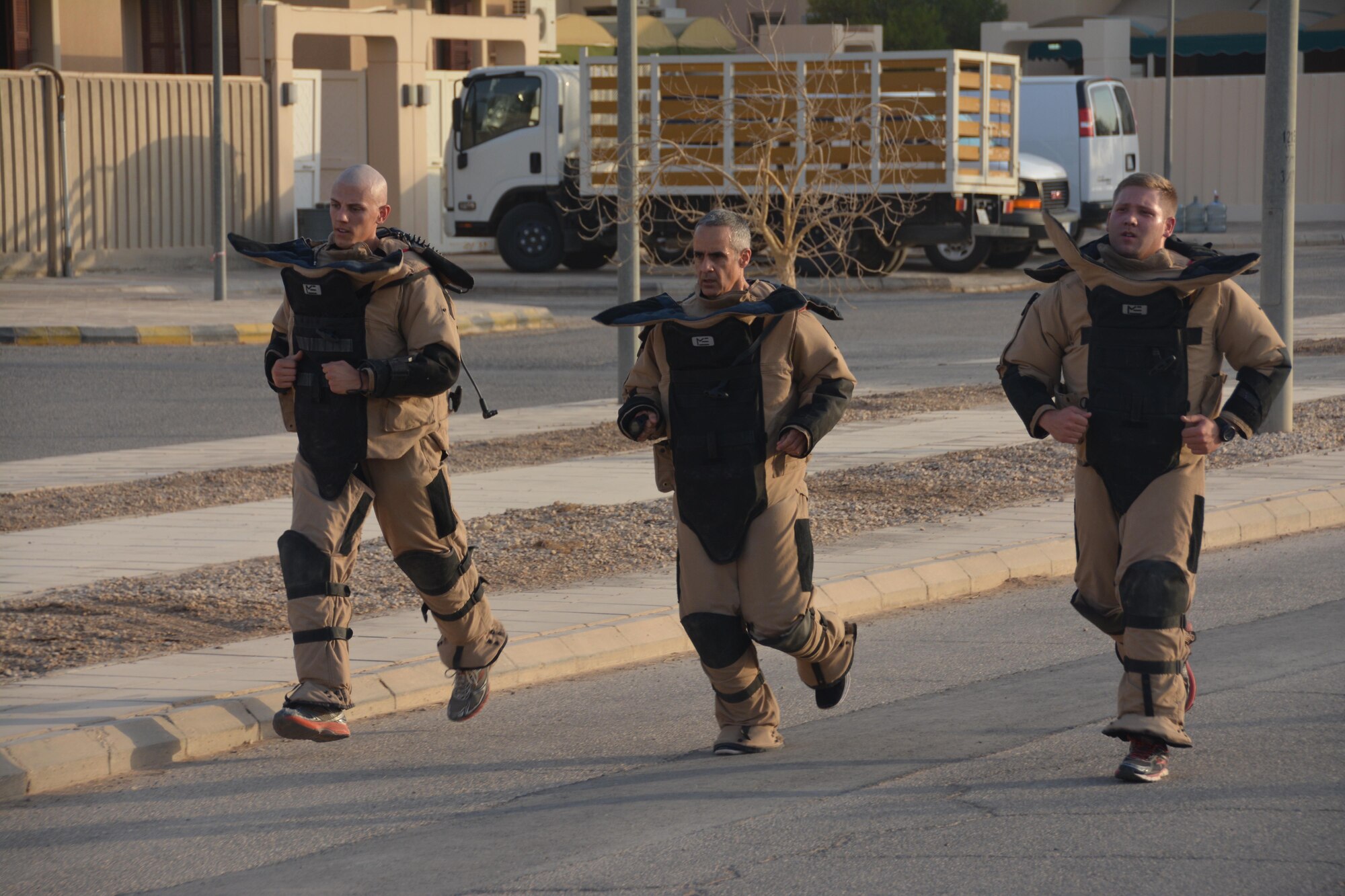Air Forces Central Command Chief Master Sgt. Ramon Colon-Lopez runs with members of the Explosive Ordinance Disposal team during a visit to Eskan Village, Southwest Asia August 25, 2015. Chief Colon-Lopez and the team members conducted the run in explosive ordinance bomb disposal suits to simulate conditions in which explosive ordinance disposal technicians may have to operate. (Courtesy photo)