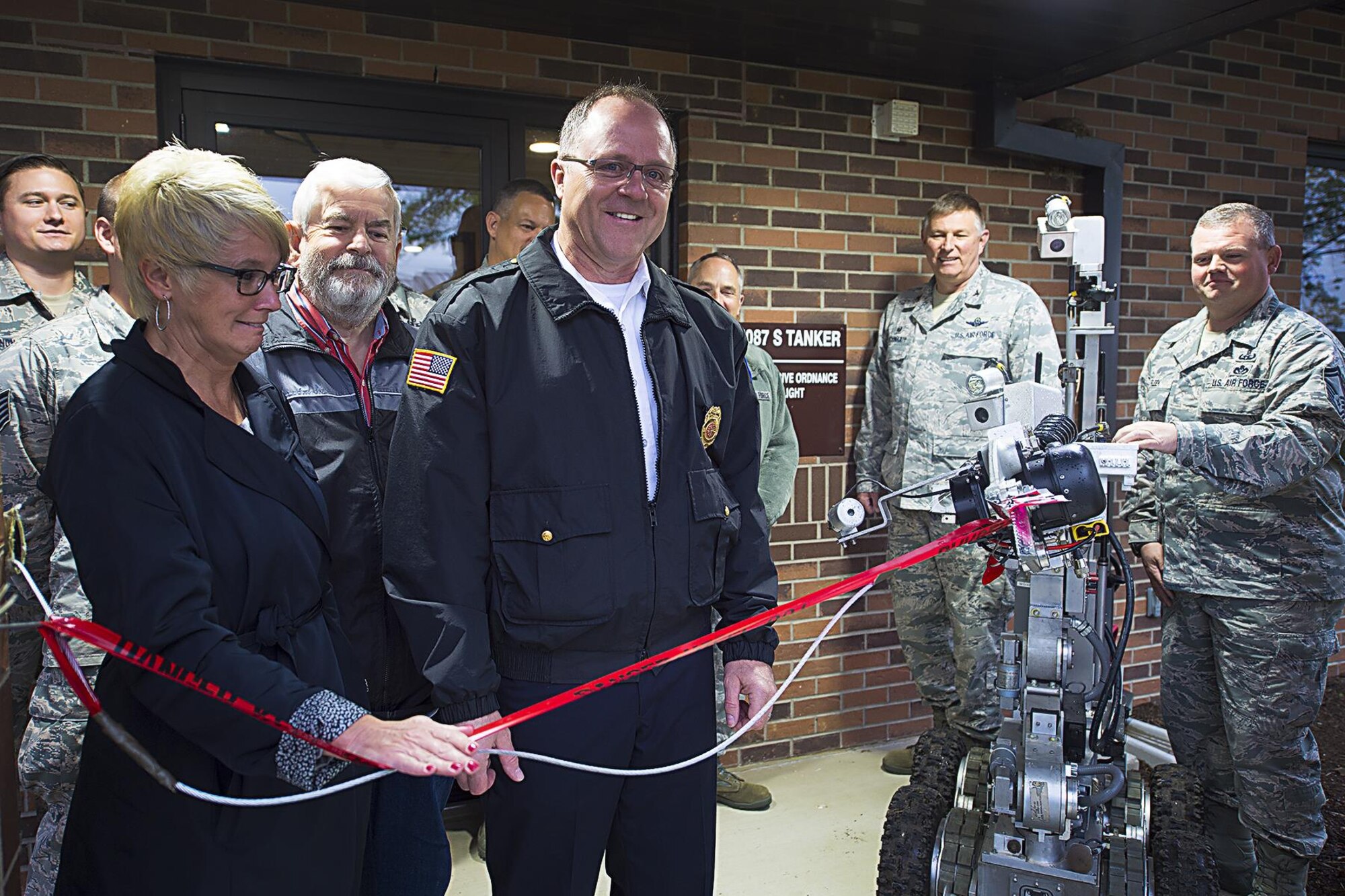 Christy Householder, Cass County economic development agency and 434th Operations Support Squadron honorary commander, assists a robot operated by Senior Master Sgt. Scott Fleek 434th Civil Engineer Squadron explosive ordnance disposal flight chief, to cut the ribbon on a new EOD facility at Grissom Air Reserve Base, Indiana May 9, 2016. The two are joined by representatives of Grissom’s leadership, EOD team, and area civic leaders. (U.S. Air Force photo/Douglas Hays)