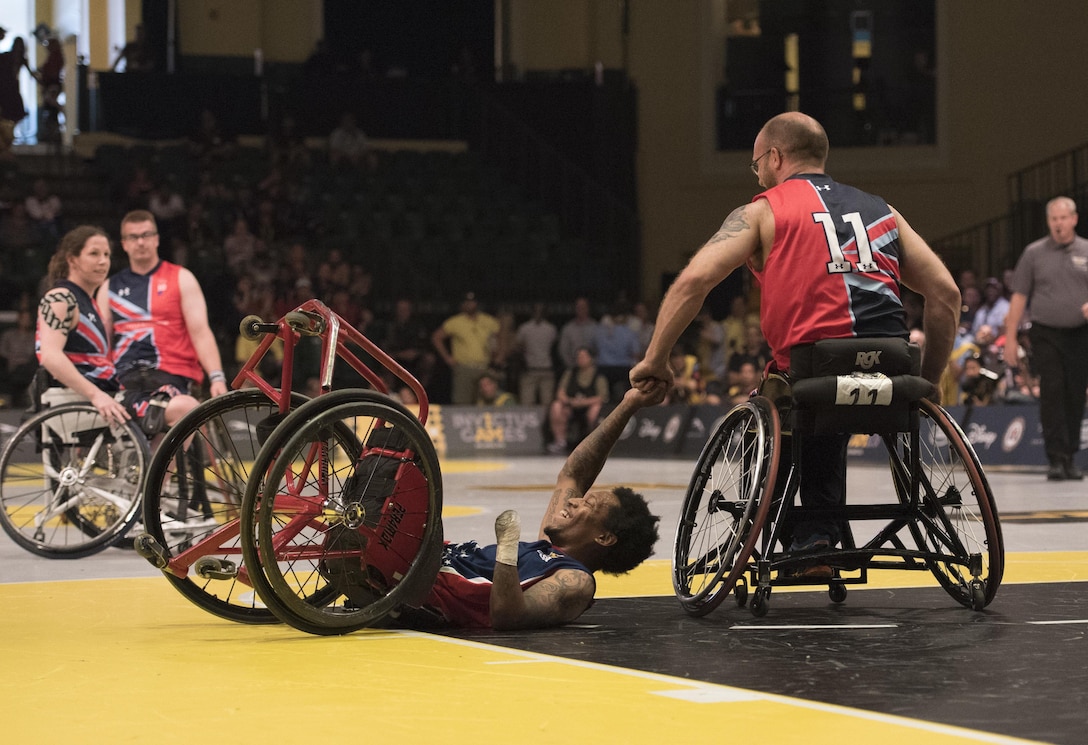 Marine Corps veteran Anthony McDaniel, foreground left, receives an assist from Great Britain’s Adam Nixon after taking a spill during the gold medal wheelchair basketball competition at the 2016 Invictus Games in Orlando, Fla., May 12, 2016. DoD photo by Roger Wollenberg