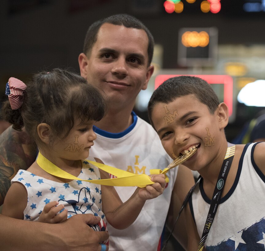 Navy veteran Javier Rodriguez poses for a photo with two of his children after winning a gold medal in wheelchair basketball at the 2016 Invictus Games in Orlando, Fla., May 12, 2016. DoD photo by Roger Wollenberg
