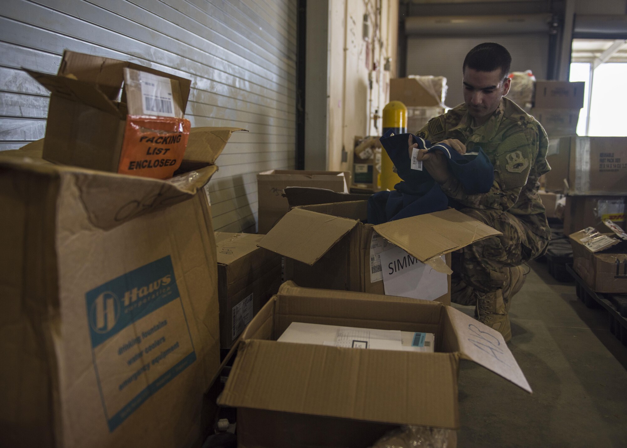 Senior Airman Michael Montalyo, 455th Expeditionary Logistics Readiness Squadron Traffic Management Office, looks through a cargo box full of uniforms at Bagram Airfield, Afghanistan, May 13, 2016. Montalyo joins the Bargram community, for the second time, from the 60th Aerial Port Squadron out of Travis Air Force Base, California. (U.S. Air Force photo by Senior Airman Justyn M. Freeman)
