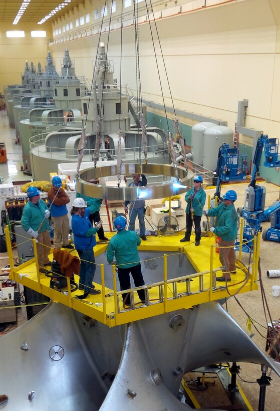 Workers assembling the new high-tech replacement turbine for Ice Harbor’s hydroelectric generator Unit-2 apply heat to expand a metal ring that will lock together the turbine segments from the inside of its hub as the ring cools and shrinks back to normal size. 
