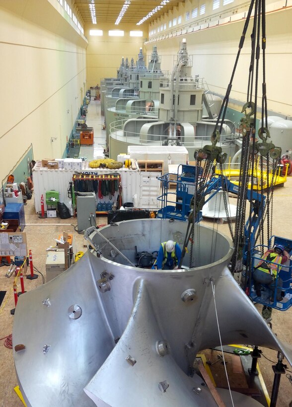 Workers assembling the new high-tech replacement turbine for Ice Harbor’s hydroelectric generator Unit-2 apply heat to expand a metal ring that will lock together the turbine segments from the inside of its hub as the ring cools and shrinks back to normal size. 