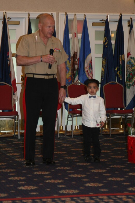 Commandant of the Marine Corps, General Robert Neller, takes the hand of a young participant separated from his family during the Commandant of the Marine Corps (CMC) Combined Awards Ceremony and uses the opportunity to finish his comments to the audience and commence meeting and greeting the families, spouses, children and guests of award recipients and ceremony attendees.