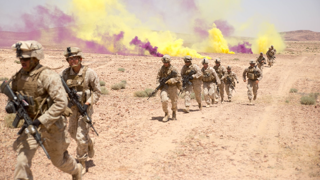 Using smoke grenades to cover their avenue of approach toward their targets, U.S. Marines from Easy Company, 2nd Battalion, 2nd Marine Regiment, charge through clouds of smoke during their last live-fire event of Eager Lion 15 around Quweyrah, Jordan, May 19, 2015. Eager Lion 16 will take place May 15-24, 2016, in Jordan. Marine Corps photo by Cpl. Ryan Young
