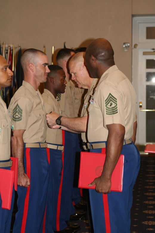 Commandant Gen. Robert Neller pins the Navy Marine Corps Commendation Medal to the uniform of a recipient at the Commandant of the Marine Corps (CMC) Combined Awards Ceremony while Sergeant Major of the Marine Corps Ronald Green assists with the duties of presenting the honors.