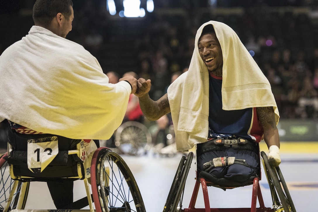 Marine Corps veterans Eric Rodriguez, left, and Anthony McDaniel fist bump as the U.S. team takes a timeout against the British team during the gold medal wheelchair basketball competition at the 2016 Invictus Games in Orlando, Fla., May 12, 2016. DoD photo by Roger Wollenberg
