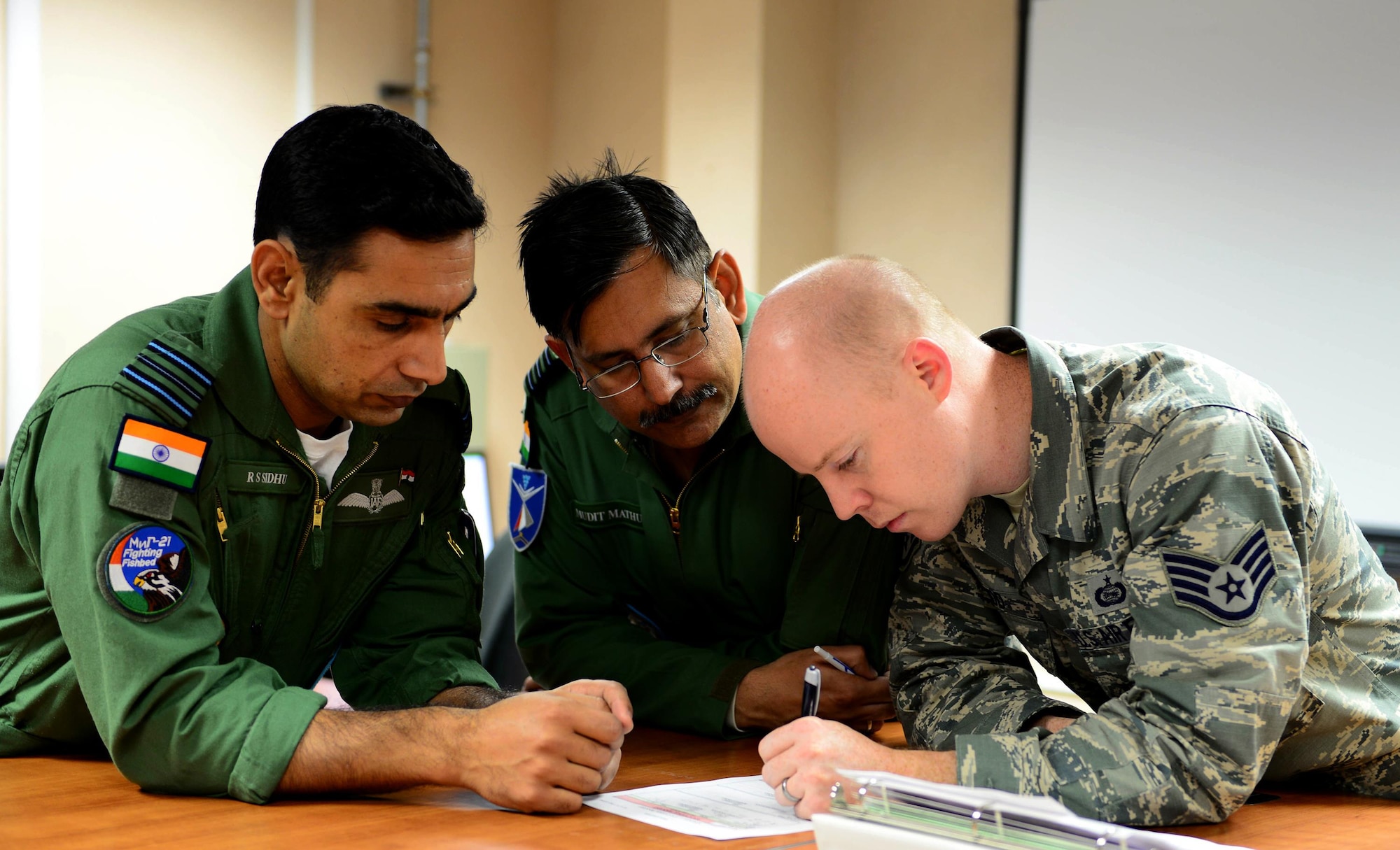 An operations airman helps Indian Air Force pilots complete a mission brief prior to a scheduled sortie, here, May 12, 2016.(U.S. Air Force photo by Airman 1st Class Cassandra Whitman)